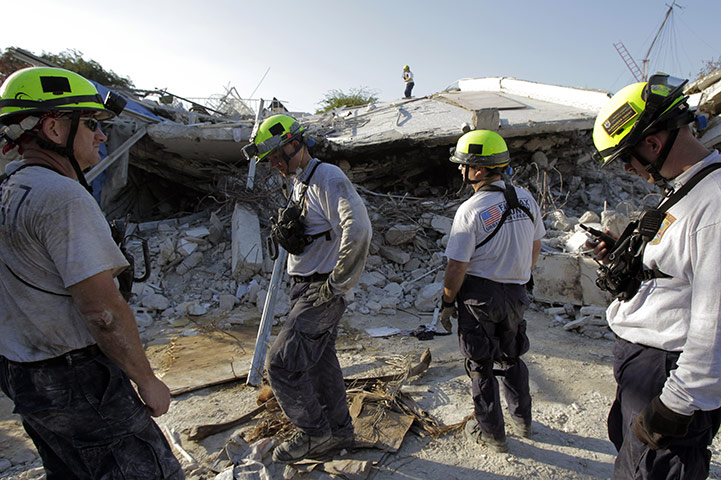Haiti one year on: January 21: Rescuers tand outside a collapsed hospital