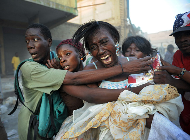 Haiti one year on: January 24: A street vendor tries to keep the crowd from stealing her goods