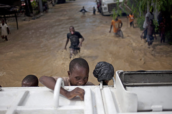 Haiti one year on: November 6: A boy holds on to a truck after hurricane Tomas