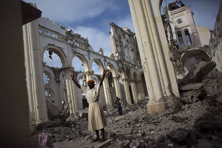 History of Haity: A woman prays among the rubble of the damaged cathedral in Port-au-Prince