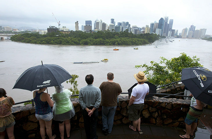 Queensland floods: People at Kangaroo Point Cliffs watch an emergency vessel on the river