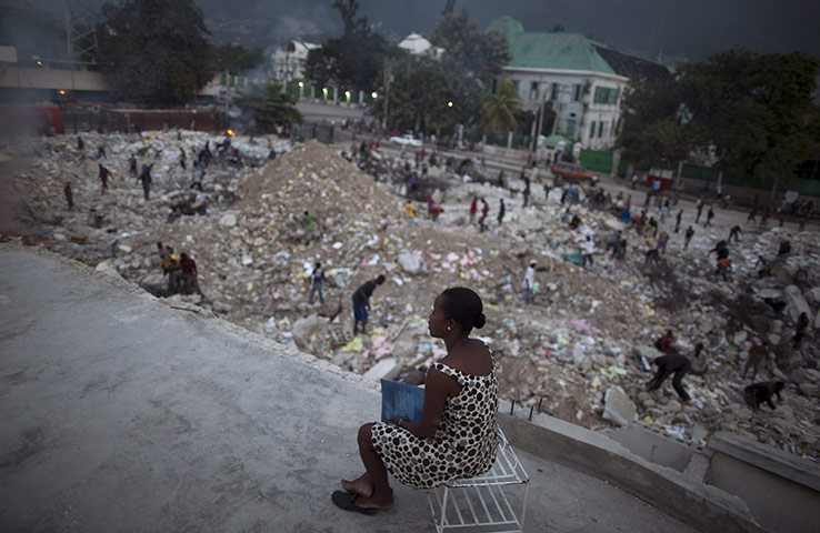 Haiti one year on: September 30: A woman watches people scavenge for metal