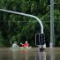 Brisbane floods: Residents use a boat to navigate across their flooded suburb