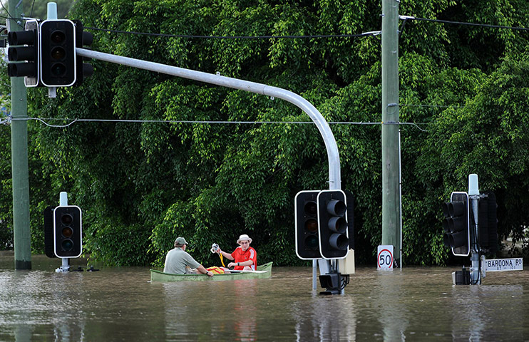 Brisbane floods: Residents use a boat to navigate across their flooded suburb