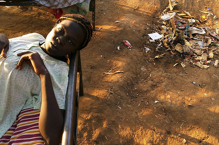 Southern Sudanisn: A woman rests on her bed at an encampment at a port, Sudan