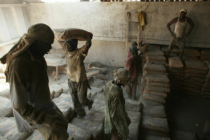 Southern Sudanisn: Men carry cement off of a barge at a port, Sudan