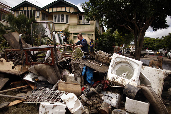 Brisbane Cleanup: A man adds to a pile of debris on the edge of a street