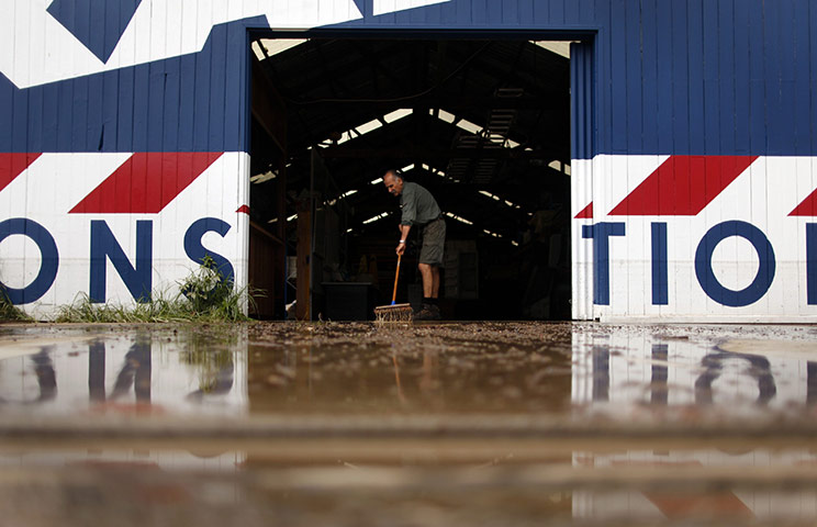 Brisbane Cleanup: A man sweeps mud out of a flood-damaged workshop