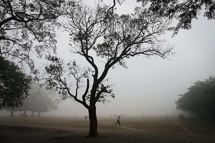 24 Hours: Indians walk in an open area enveloped in dense fog in Calcutta