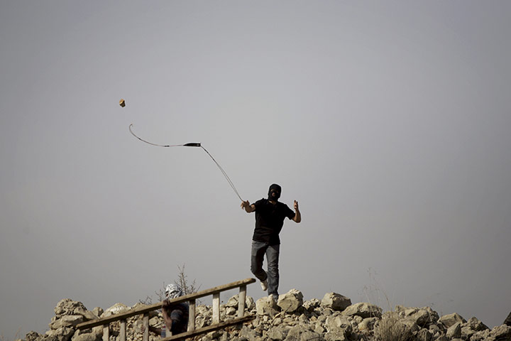 24 Hours: A Palestinian uses a slignshot to hurl a stone at Israeli troops in Nilin
