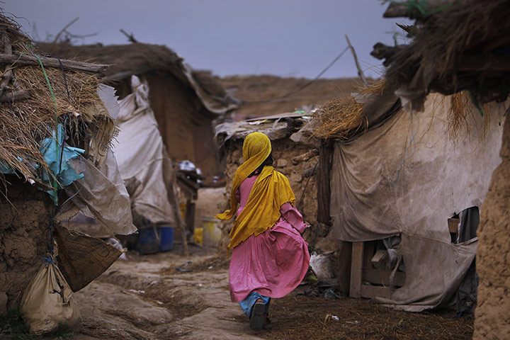 24 Hours: An Afghan refugee girl walks through an alley of a slum in Islamabad
