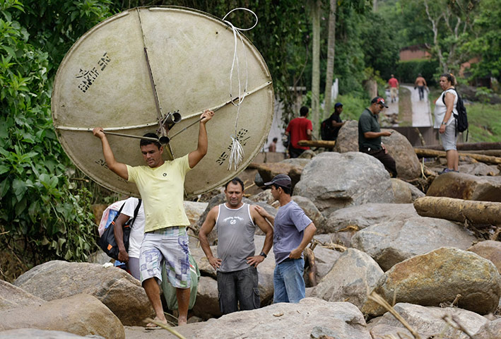 Brazil aftermath: A man carries a satellite dish recovered after a landslide in Campo Grande 