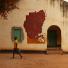 Sudan election: A woman walks by a building with a map of Sudan painted on it