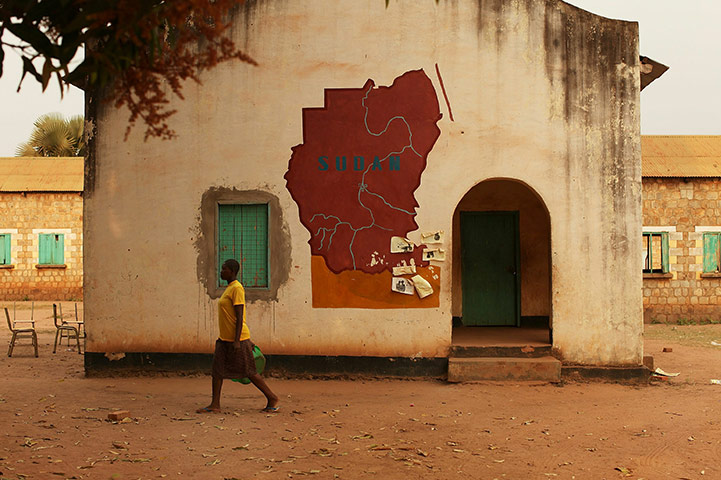 Sudan election: A woman walks by a building with a map of Sudan painted on it