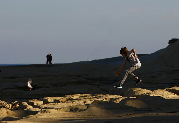 24 hours in pictures : A young boy jumps towards a pigeonin MAlta