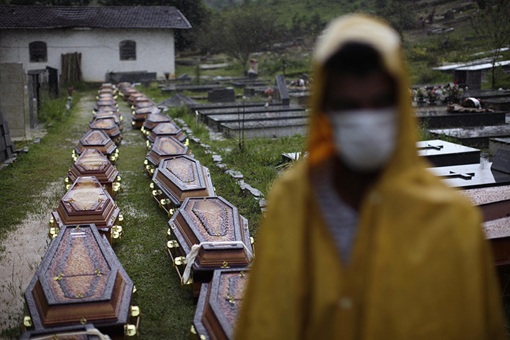 Felipe Dana in Brazil: A man stands in front of coffins at a mass funeral for landslide victims