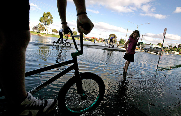 Victoria flood: Teenagers ride their bikes through a flooded street