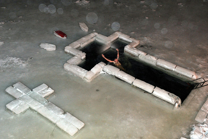 Orthodox epiphany: A man enters the waters of Komsomolskoe lake through a cutout cross in ice