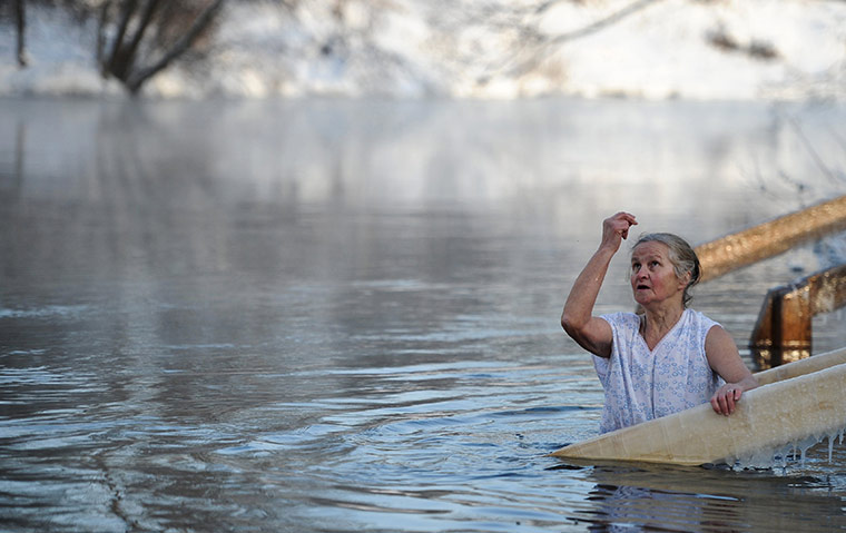 Orthodox epiphany: A woman makes a sign of the cross while standing Istra river