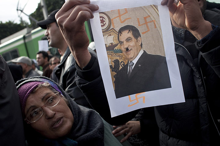 Tunisia uprising: A woman looks a picture of former President caricatured as Hitler