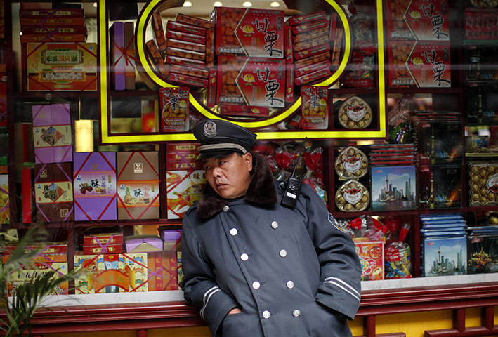 Week in business: A security guard rests next to the window of a shop in downtown Shanghai