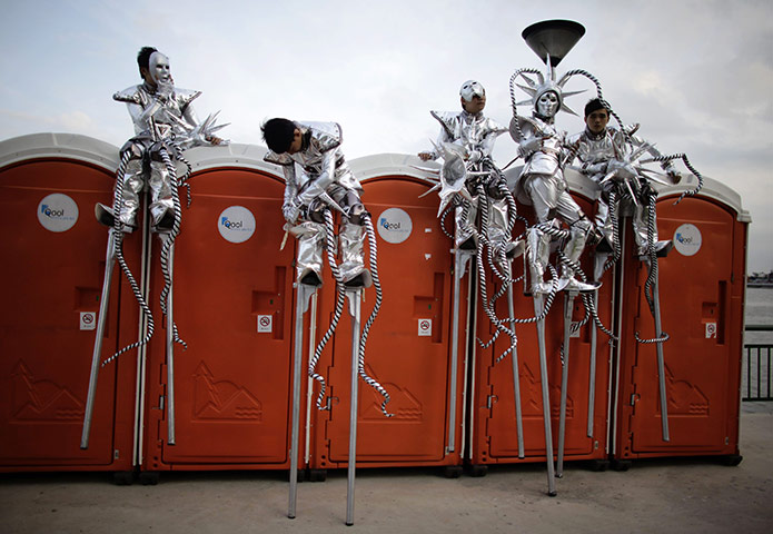 24 hours in pictures: Singapore: Performers on stilts rest beofre the Chingay parade 