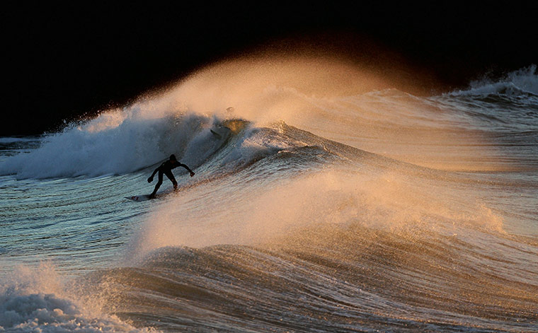 24 hours in pictures: Polzeath, England:  A surfer braves the cold winter waves