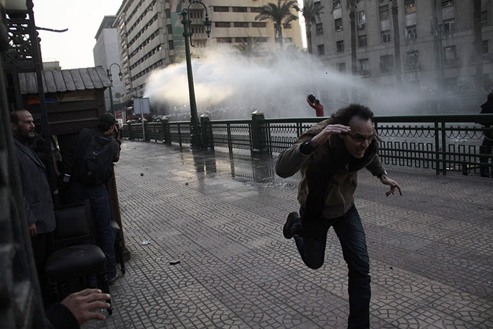 Egypt protests: A man runs from a police water cannon in Cairo
