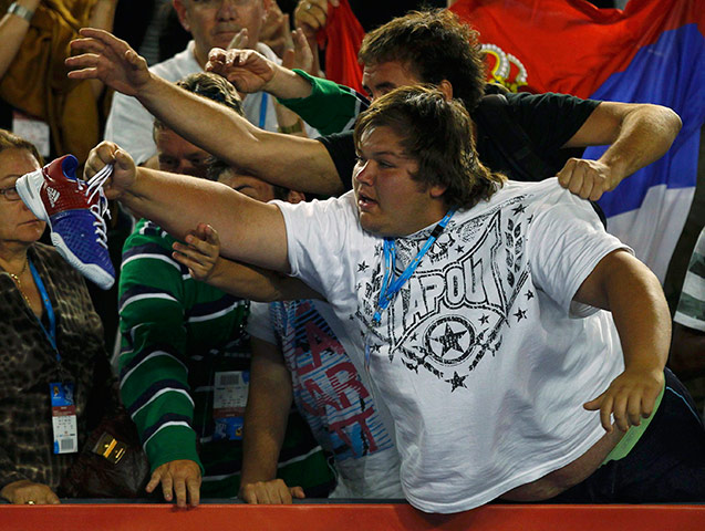 Melbourne Day 11: A spectator catches the shoe of Djokovic after his match against Federer