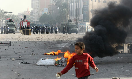 A child walks past burning tyres as demonstrators battle police during a demonstration in Suez