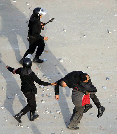 Egypt Protests: Police officers carry an injured colleague in Suez