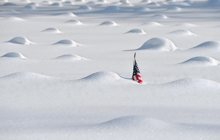 24 hours in pictures: A flag pokes above snow in covered grave markers n Veterans Memorial Field