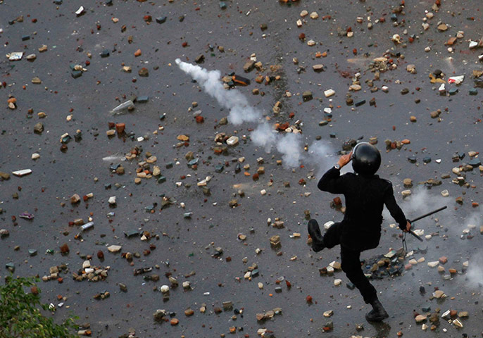 24 hours in pictures: A police officer kicks away a tear gas canister, Egypt
