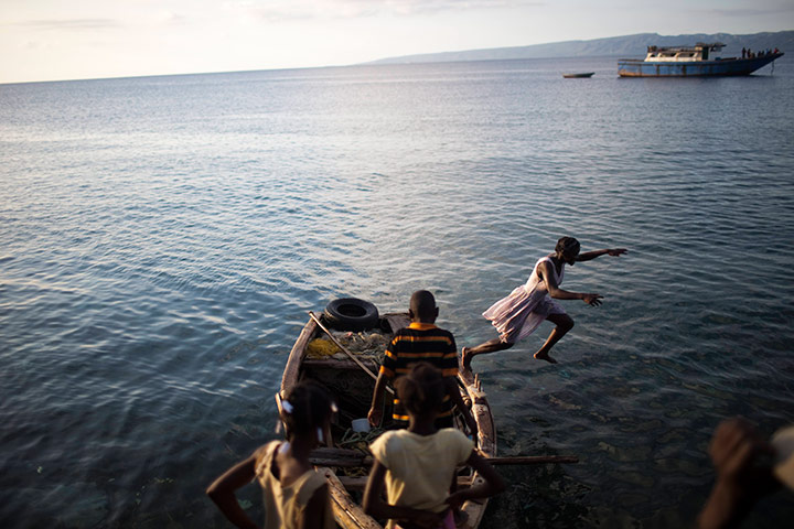 24 hours in pictures: A girl jumps from a boat into the ocean in Port-du-Paix