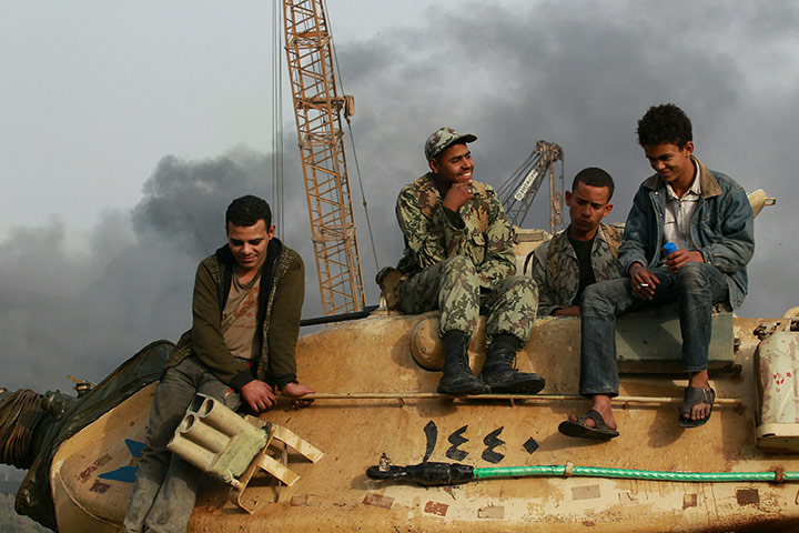 Egypt 29 January: People sit on an army tank in Tahrir Square in Cairo