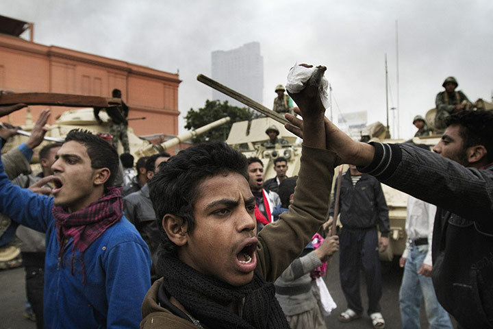 Egypt 29 January: Egyptian demonstrators chant slogans in front of army tanks in Cairo