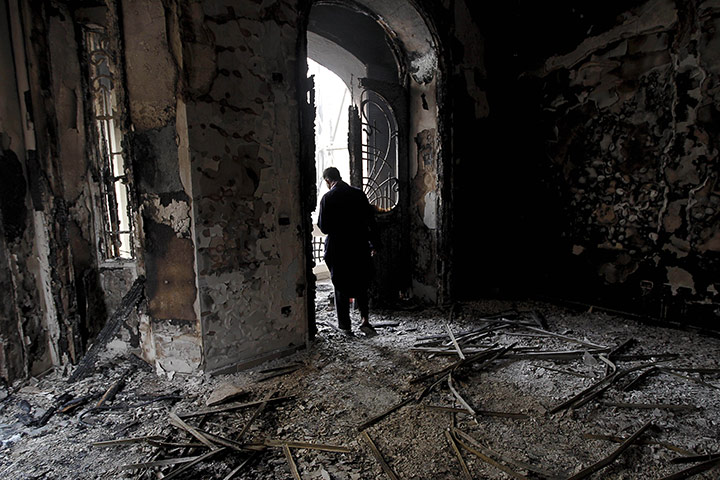 Egypt 29/01: An Egyptian man surveys the fire damage at a burned police station