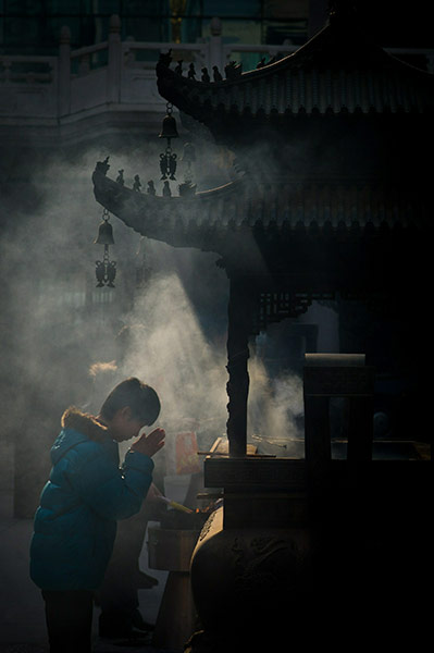 24 hours in pix: A man prays after burning incense sticks in Shanghai