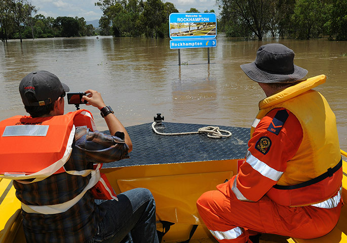 Floods in Australia: A rescue boat passes a Welcome to Rockhampton sign