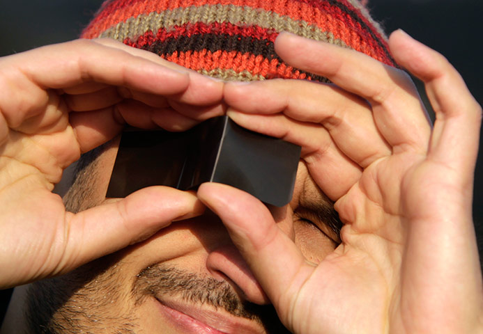 eclipse: A man looks at a partial solar eclipse over Romania, Bucharest