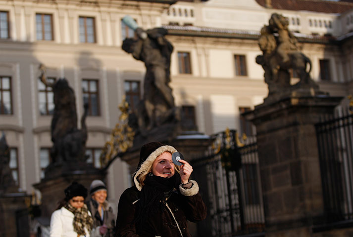 eclipse: A young woman observes a partial solar eclipse in Prague