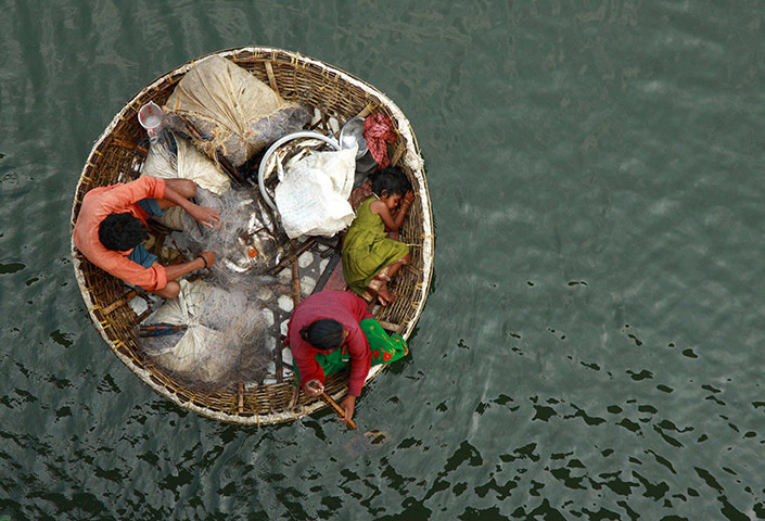 24 hours in pictures: A fisherman arranges a fishing net as his wife paddles their boat in Kochi
