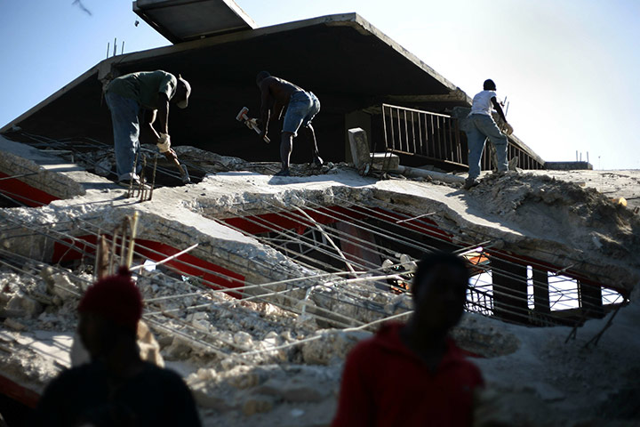 24 hours: Port-au-Prince, Haiti: Labourers demolish a destroyed building
