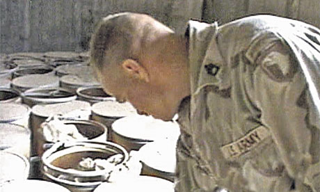 A US soldier inspects barrels of explosives, 2003.