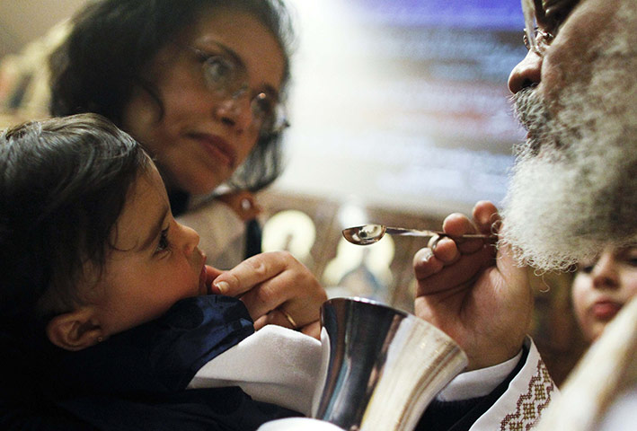Orthodox Christmas: A child receives communion from a Coptic Orthodox priest