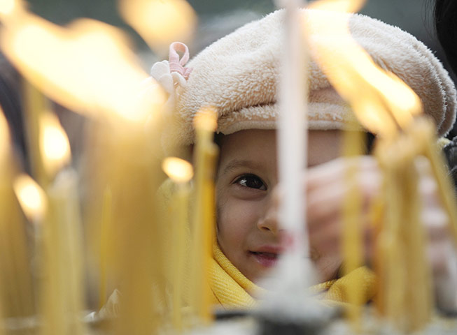 Orthodox Christmas: A girl lights candles during a Christmas liturgy in St. Clement Cathedral