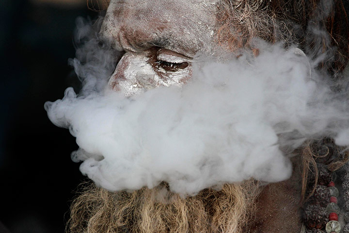 24 hours in pictures: A sadhu smokes marijuana at a transit camp in Calcutta