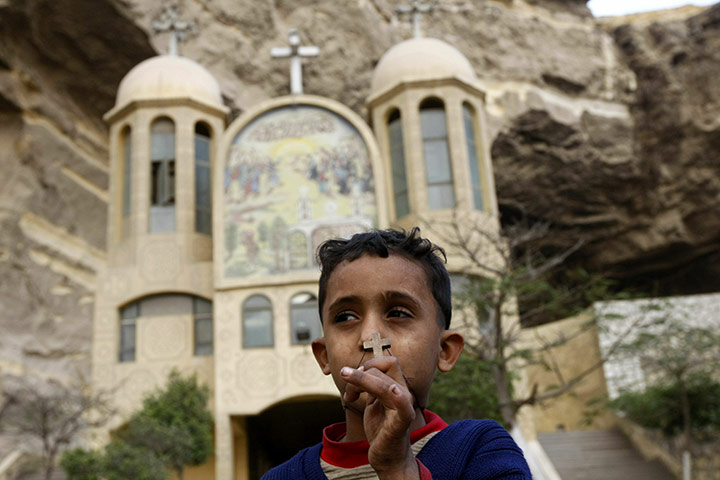 24 hours in pictures: An Egyptian Christian boy holds a cross pendant outside a Coptic church