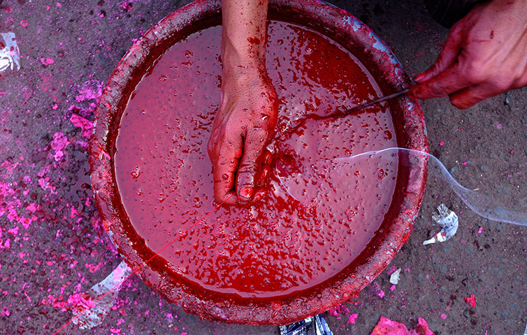 24 hours: Ahmedabad, India: An Indian man applies colours to kite string 