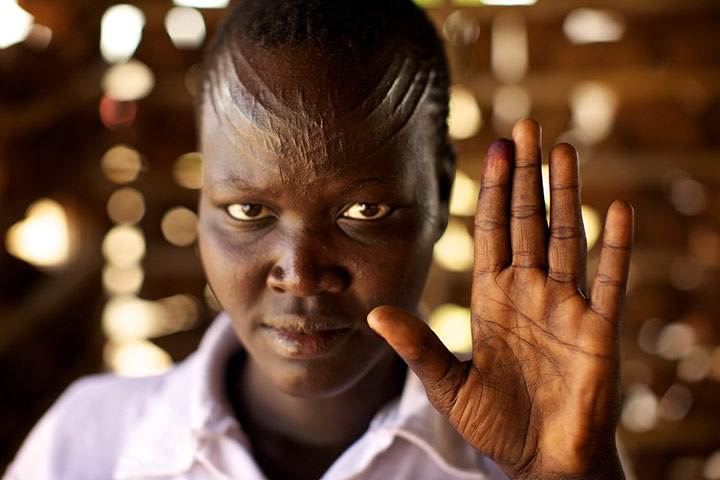Sudan voters: Rebecca Sanie holds up her ink-stained finger to show she voted